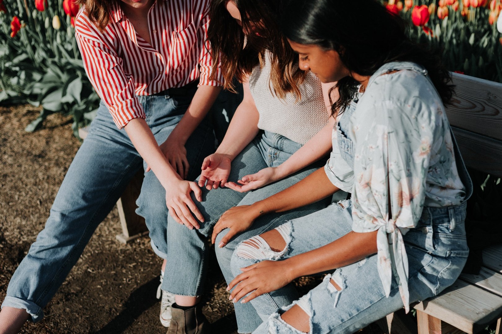 3 women sitting on a bench and praying together