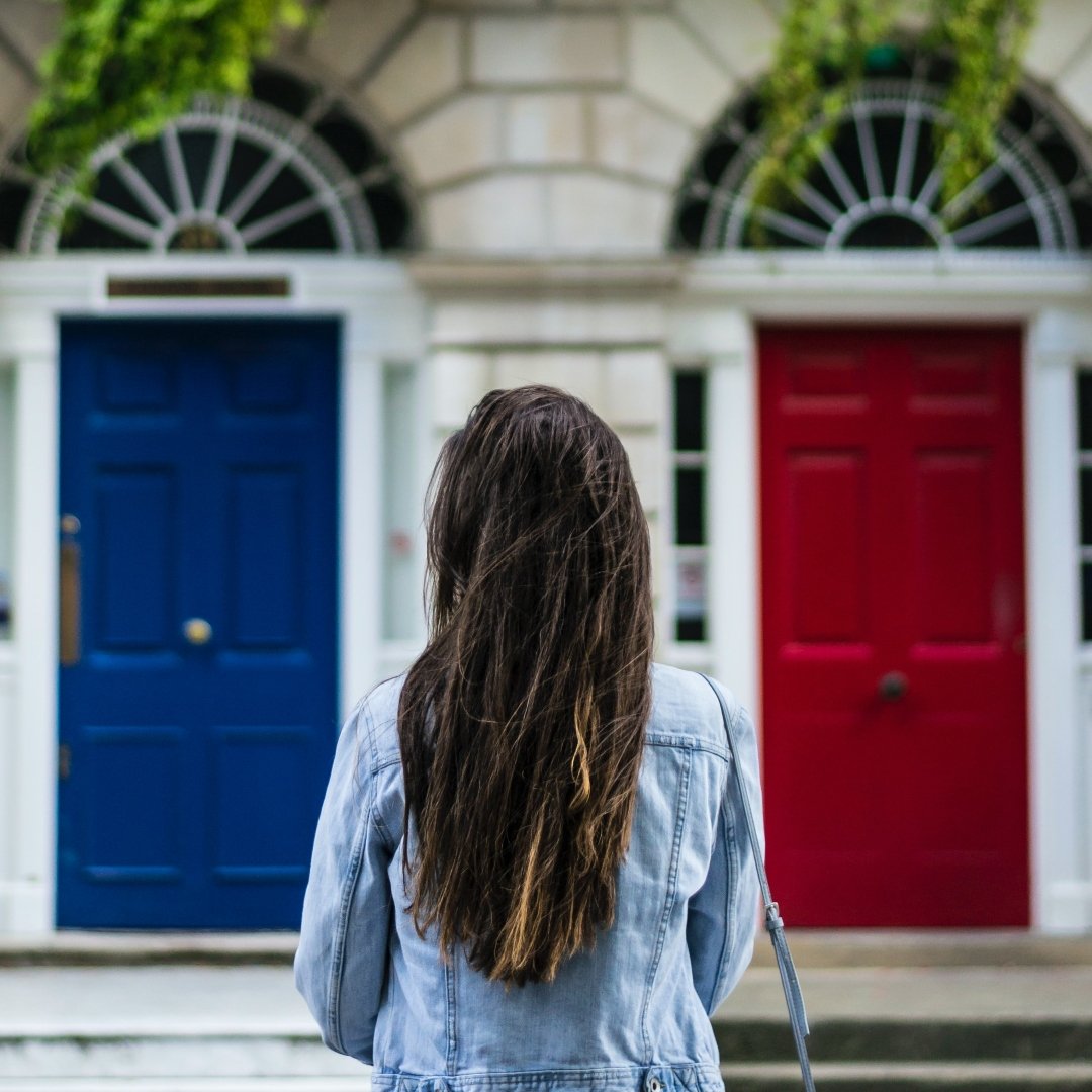 woman approaching building with blue and red doors