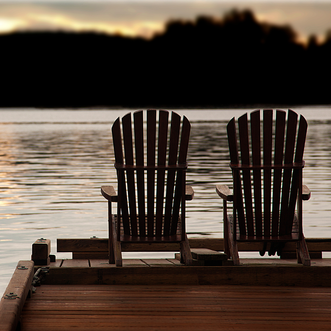 two empty chairs on a dock at sunset