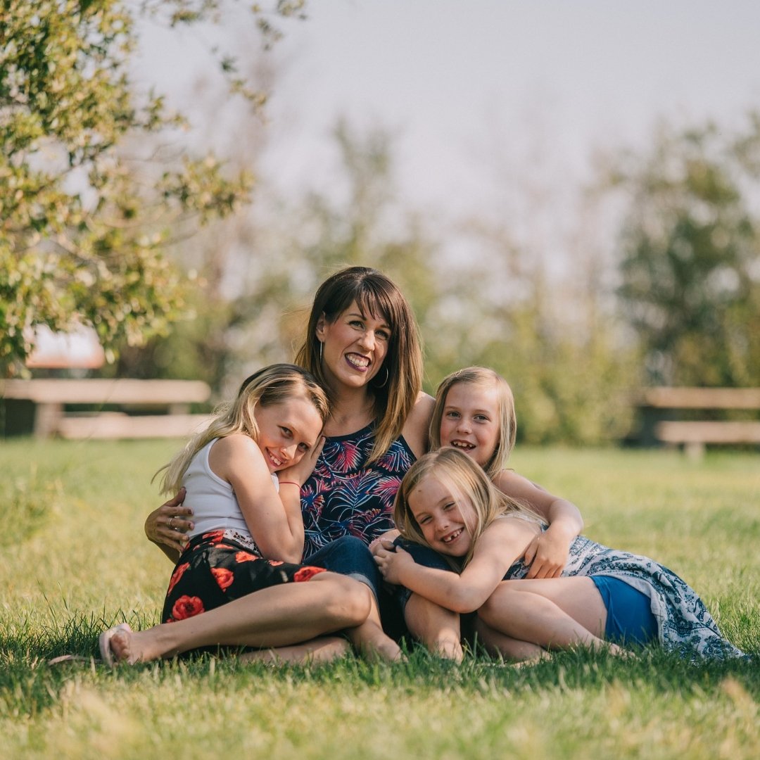 mom and 3 girls resting in the grass