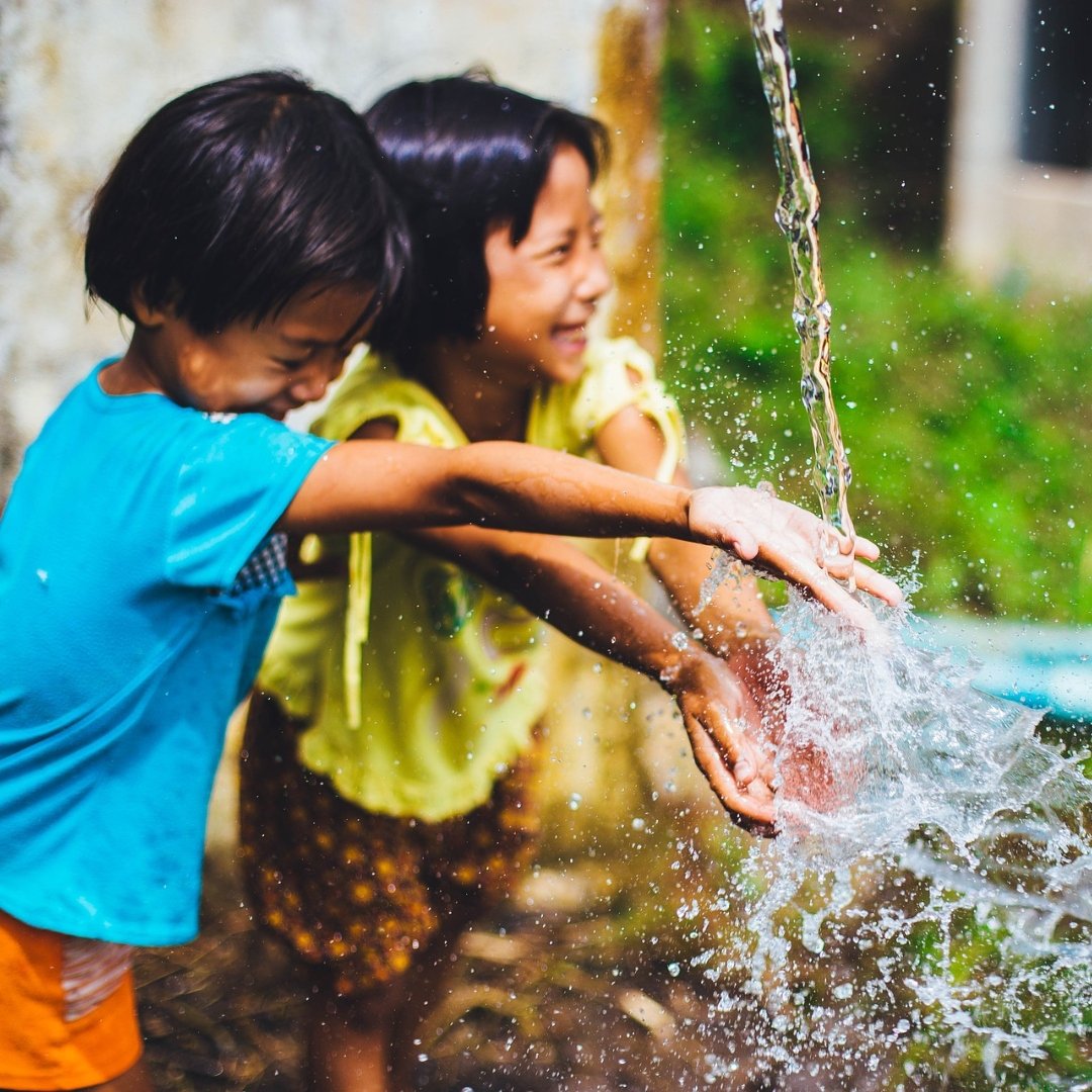 kids playing under a water faucet