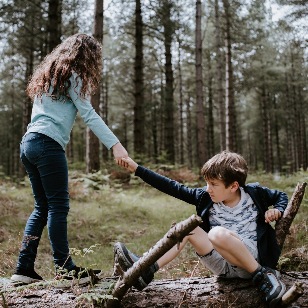 girl helping boy stand up