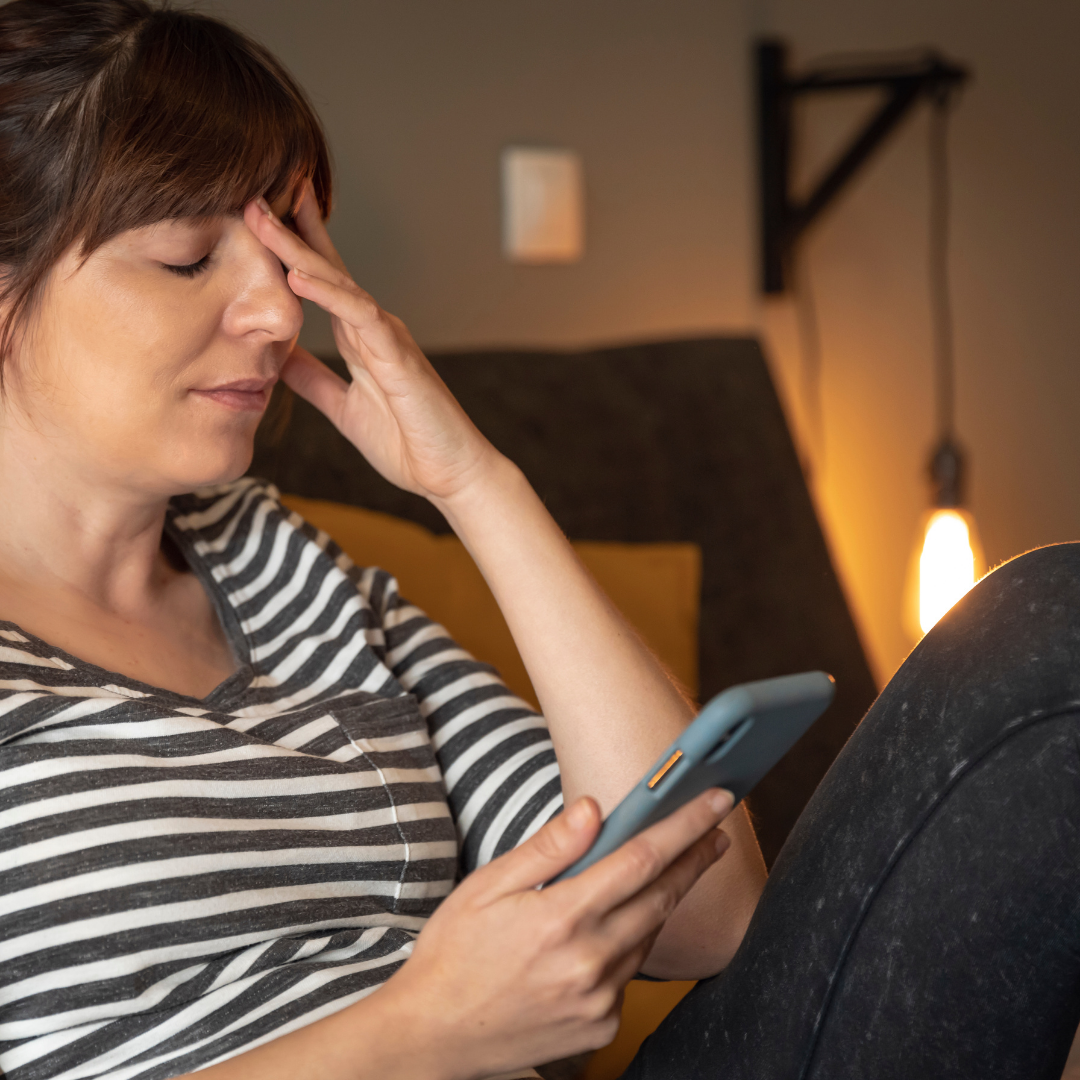woman looking sadly at cell phone