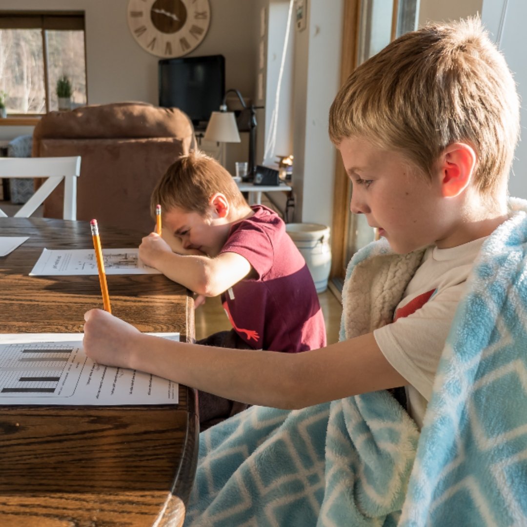 2 boys doing schoolwork at kitchen table