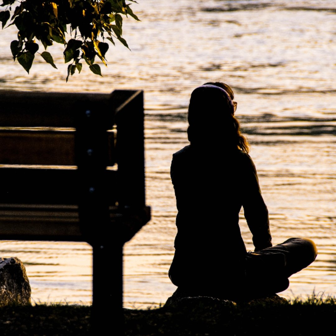 woman sitting at the edge of a river