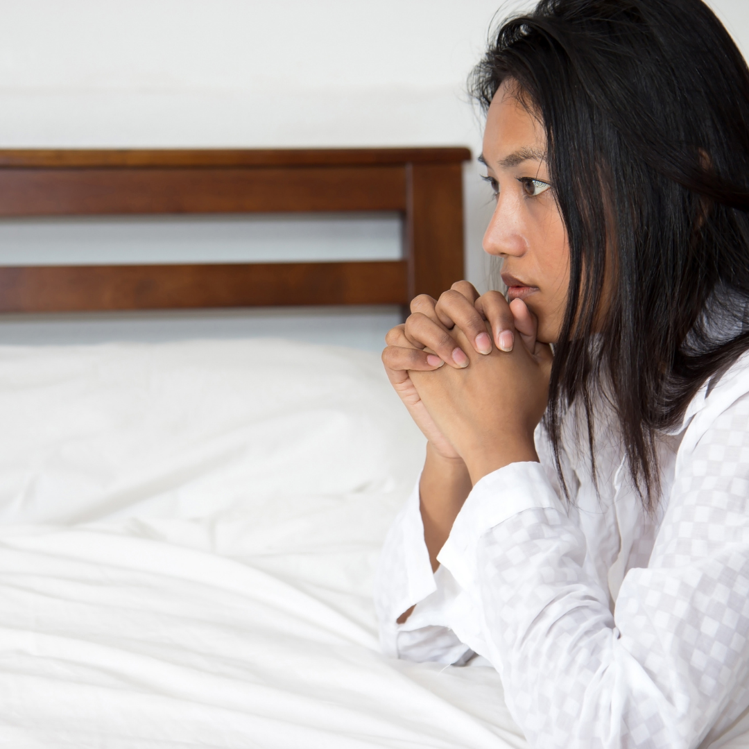 woman praying beside a bed