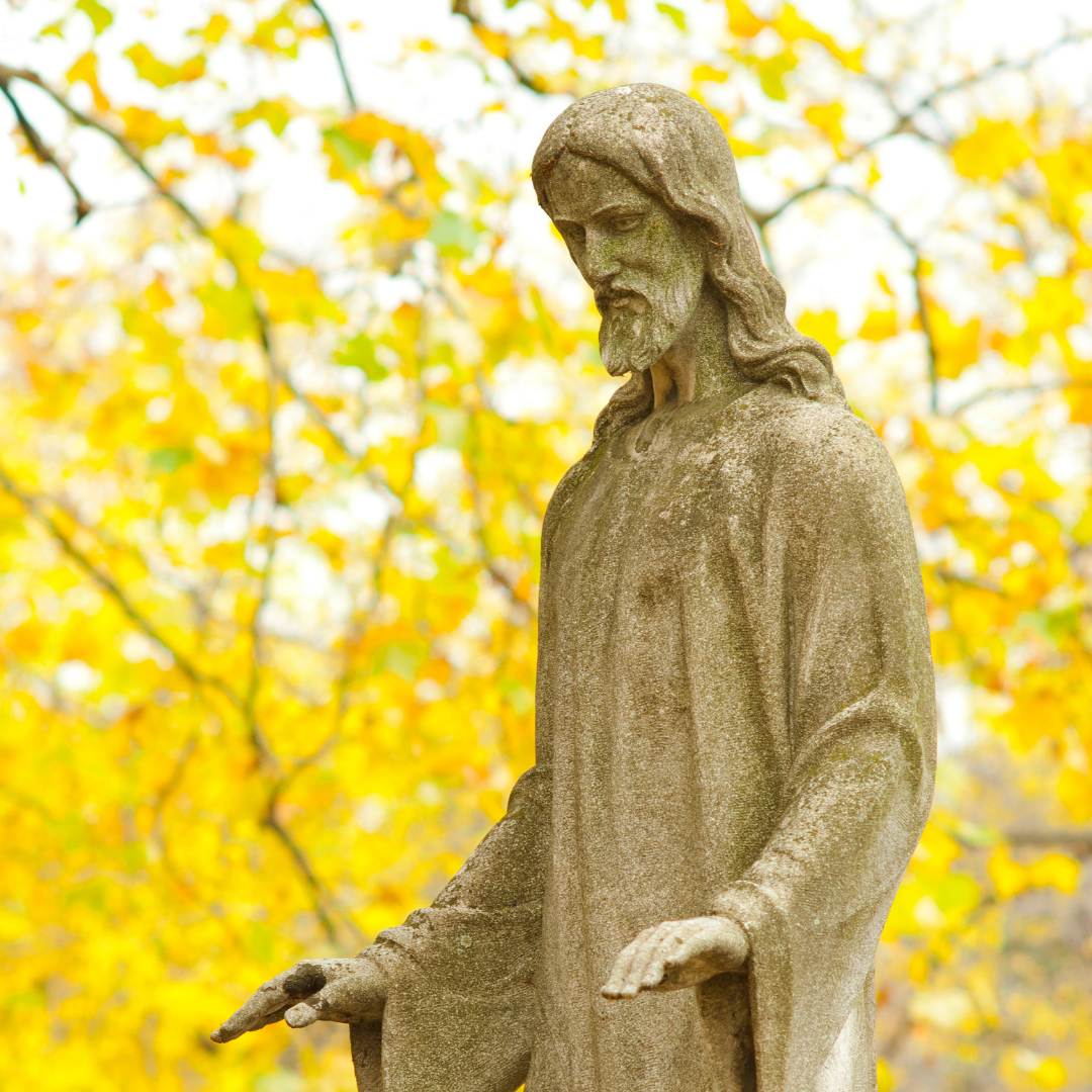 statue of Jesus with autumn leaves in the background