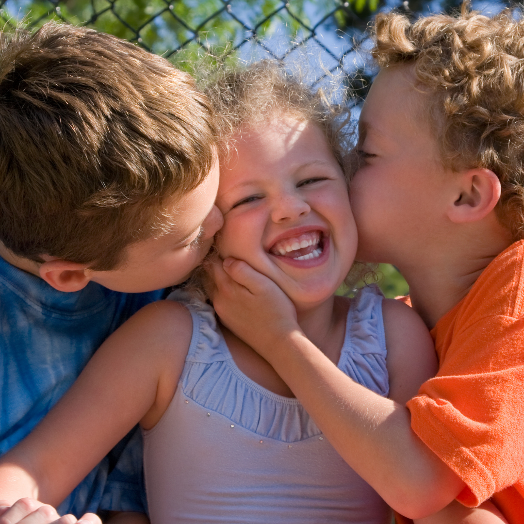 2 brothers kissing little sister on the cheek
