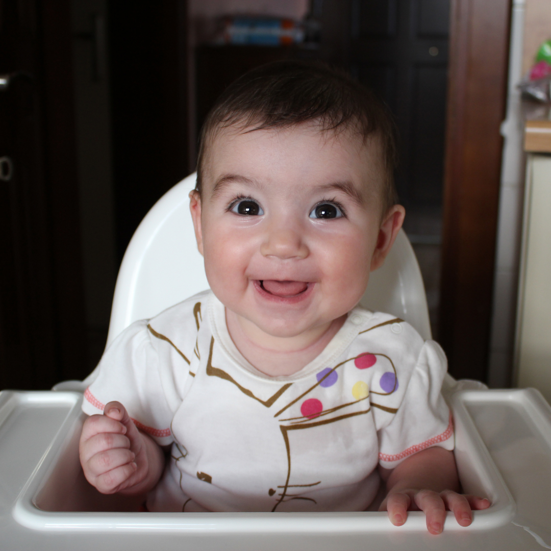 smiling baby sitting in a high chair