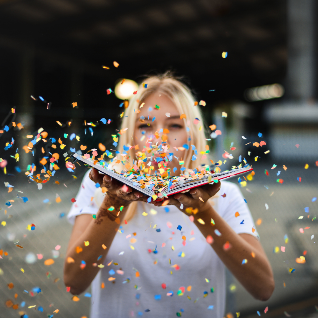 woman blowing confetti out of a book