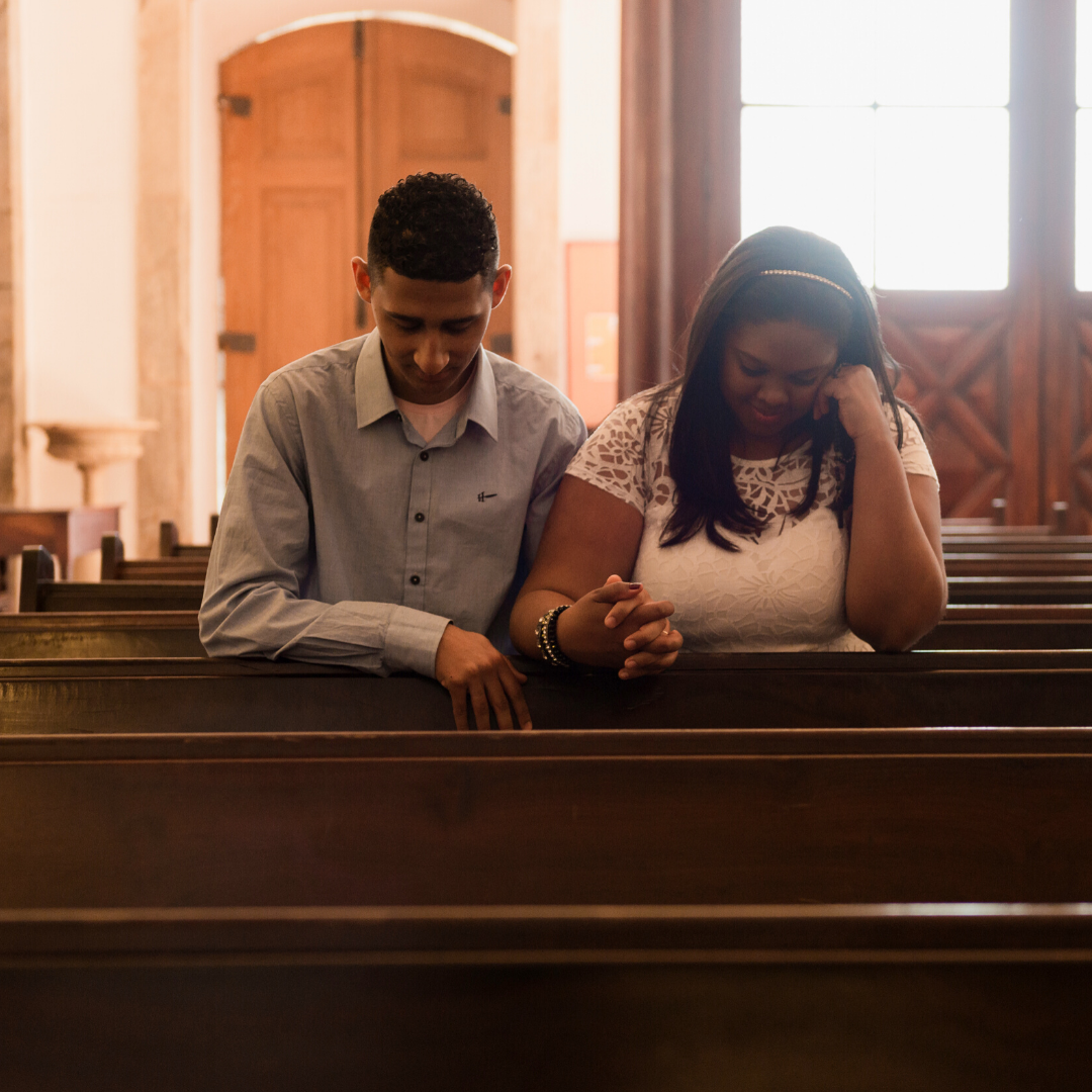 young couple praying together in a church