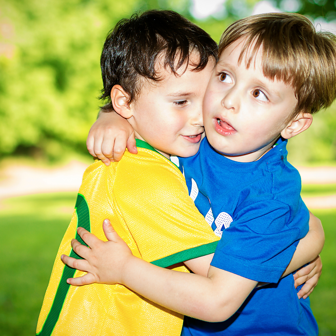 2 little boys in soccer uniforms hugging each other