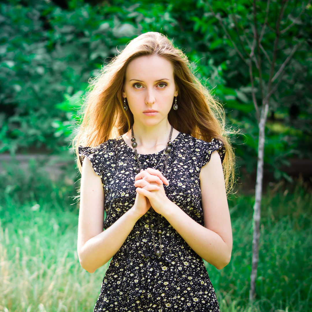 woman praying outdoors, with pleading eyes