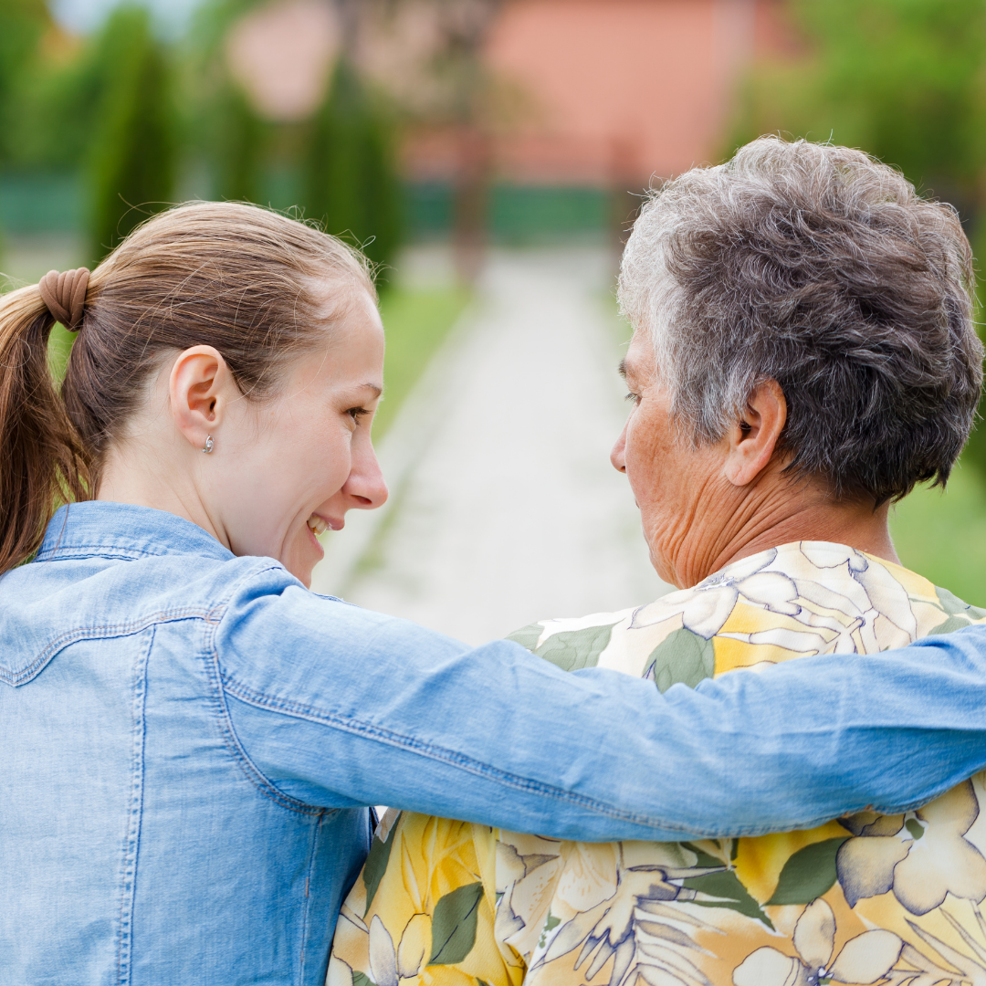 younger woman talking with older woman, with arm around her