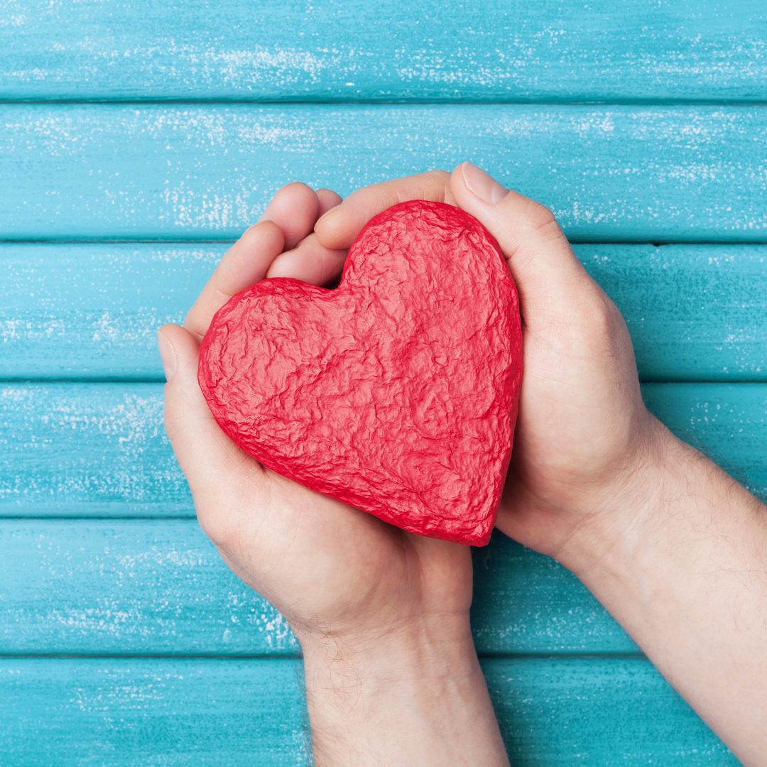 hands holding a red clay heart