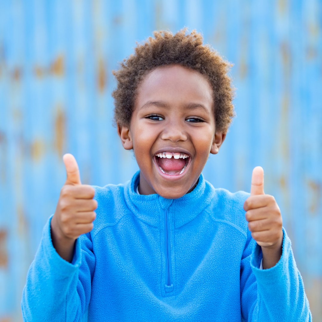 young boy holding 2 thumbs up