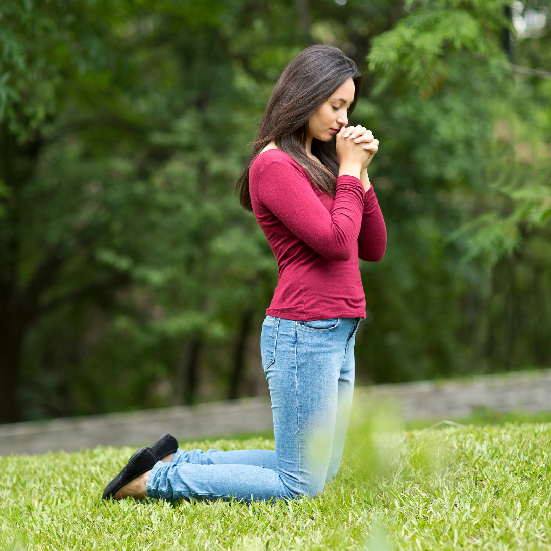 woman kneeling outdoors in prayer