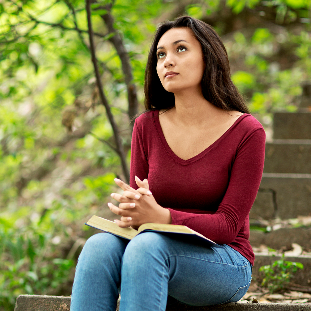 woman praying and reading the Bible outdoors