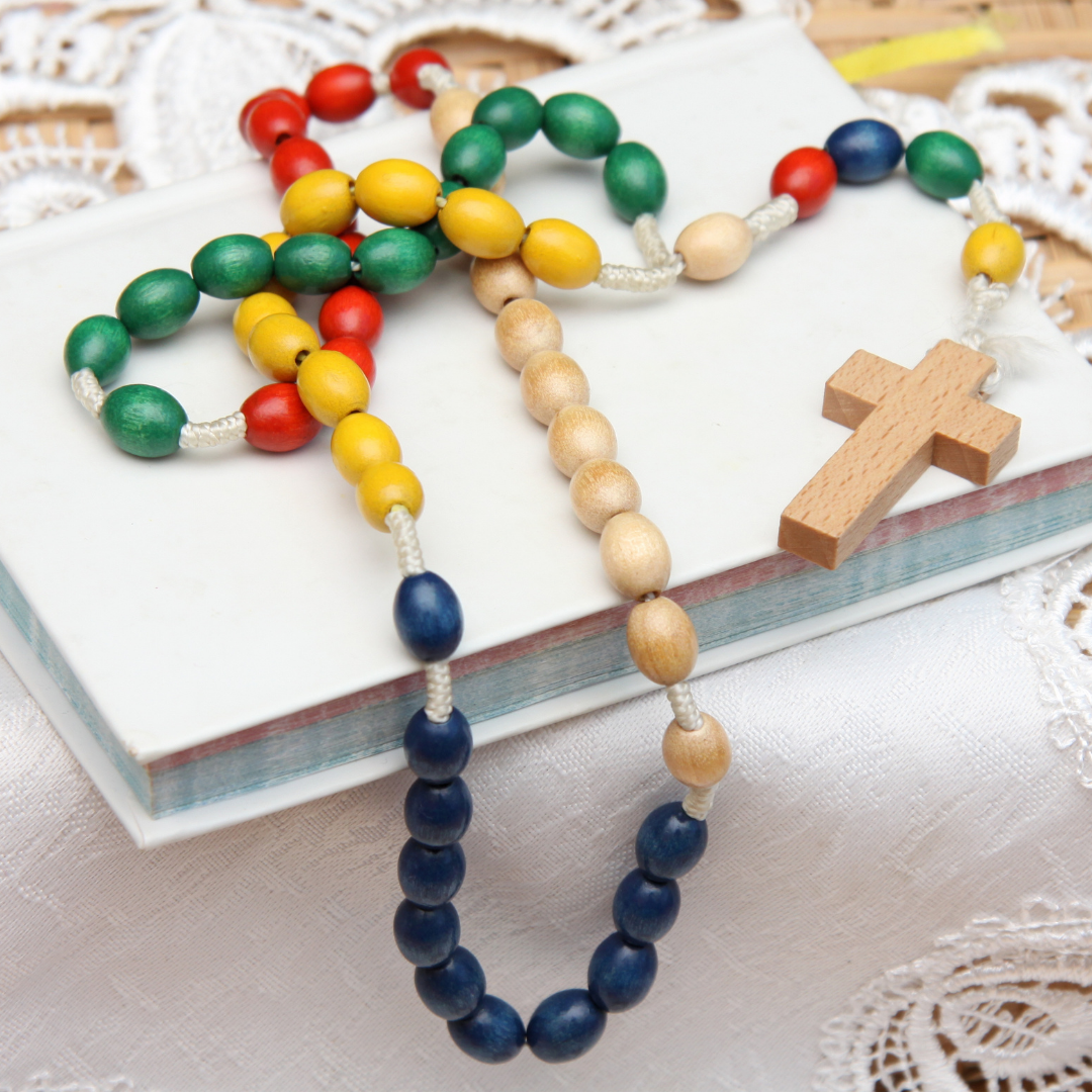 child's wooden rosary on top of prayer book
