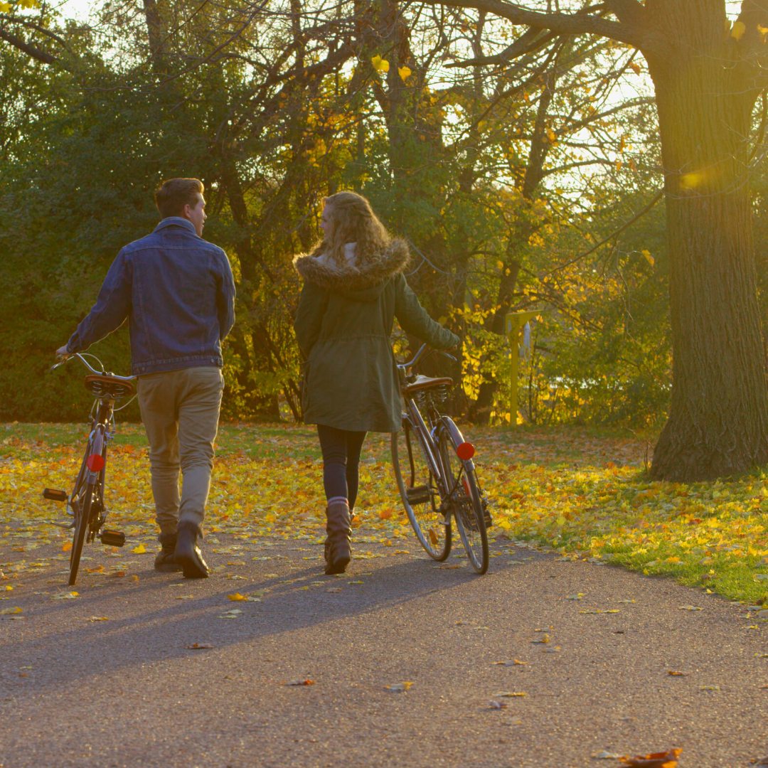 couple walking with bicycles during Autumn