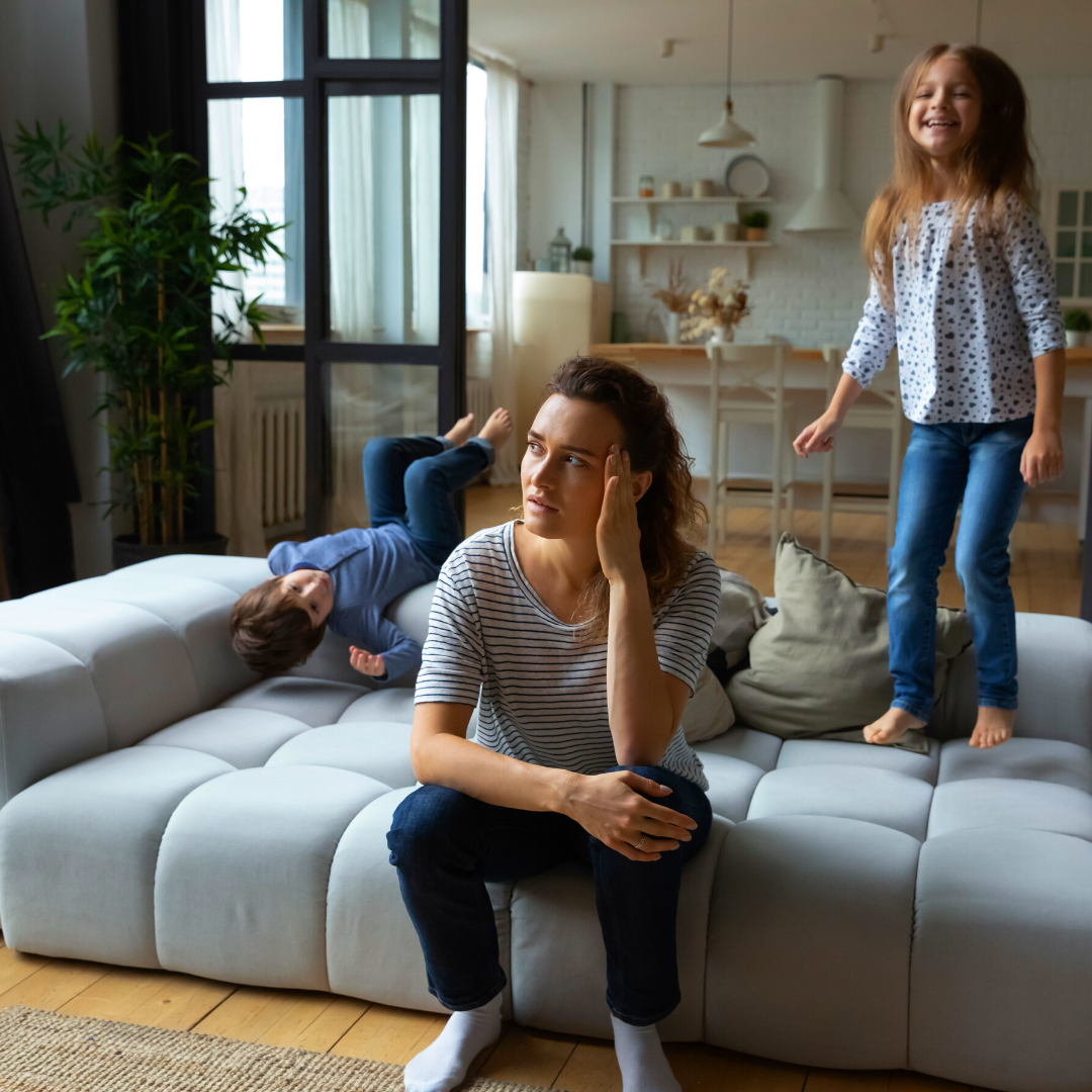 exhausted mom with 2 kids jumping on the couch