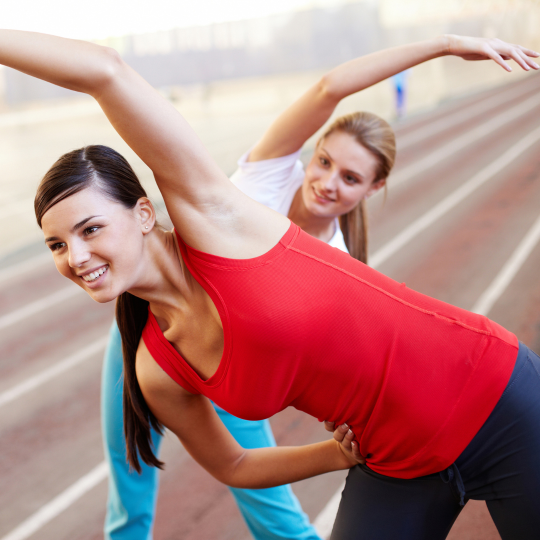 2 women stretching on a track before a run