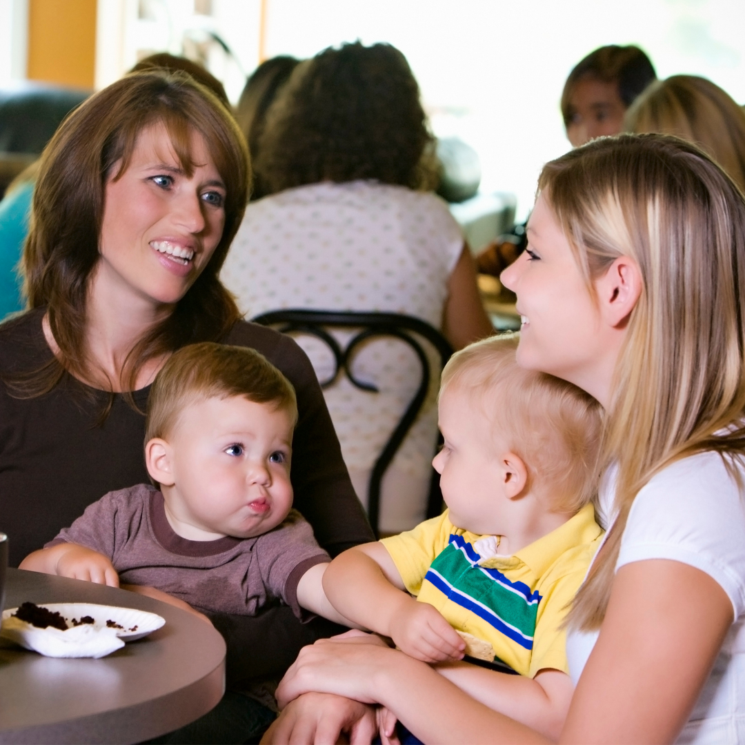 2 women with babies talking in a cafe