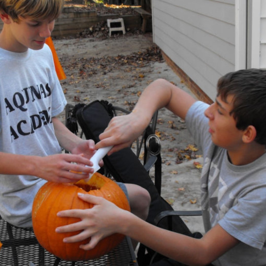 2 teenage boys carving a pumpkin