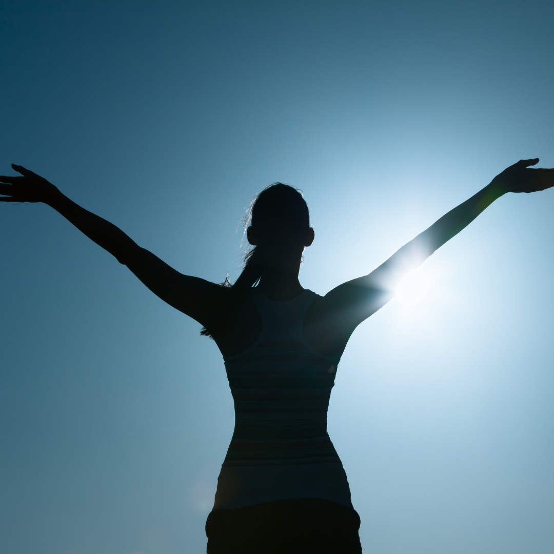 silhouette of woman raising her arms joyfully