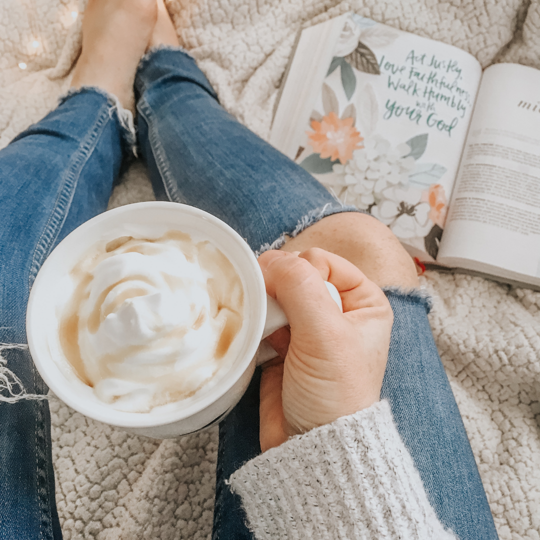 woman drinking coffee with open Bible nearby