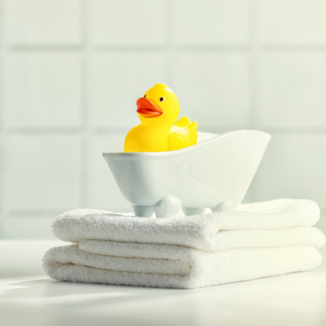 rubber ducky and towels stacked near a bathtub