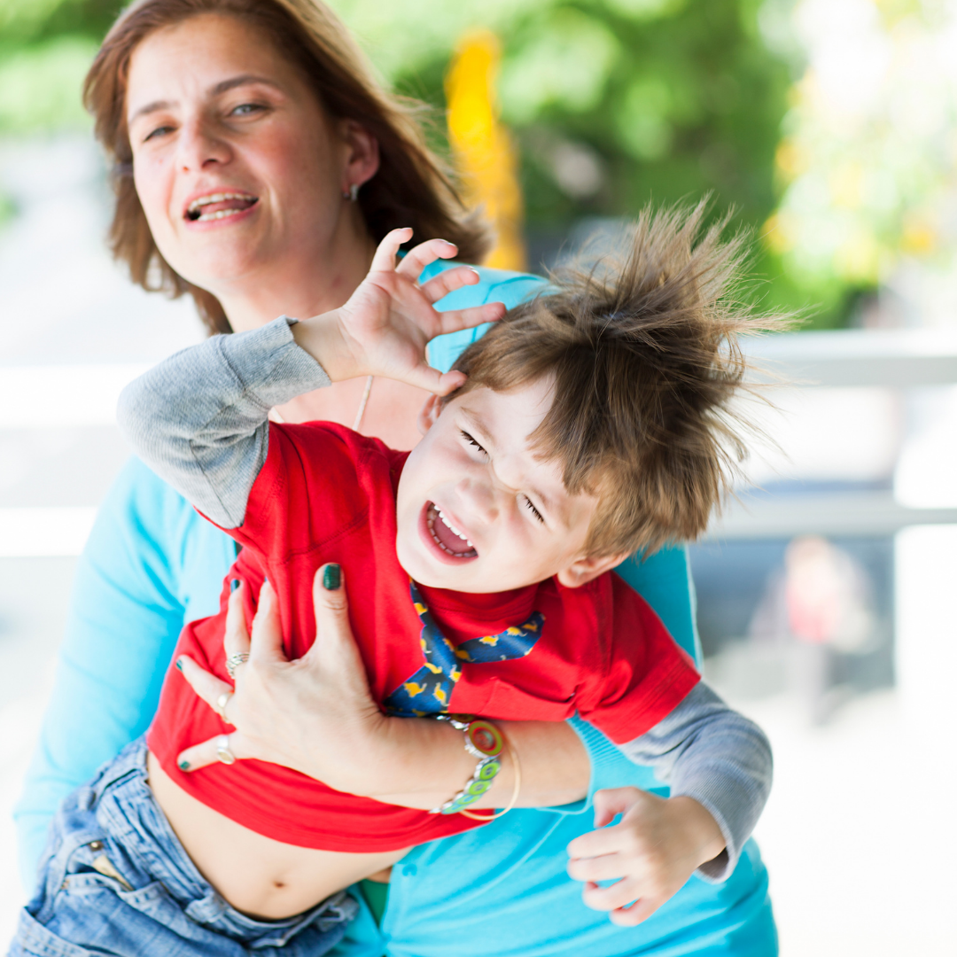 child having a tantrum, being carried by mom