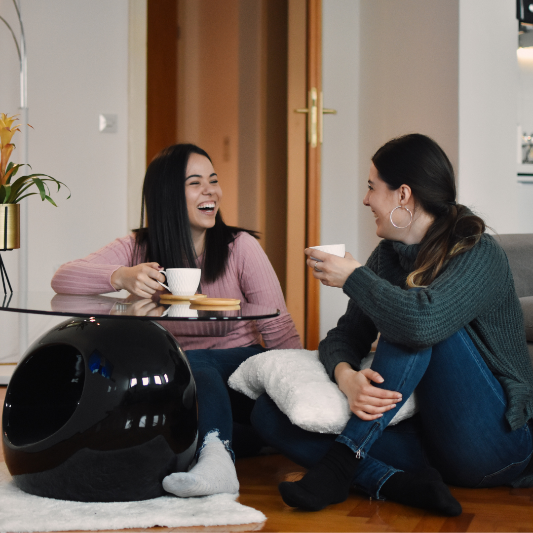 2 women sitting on the floor and drinking coffee