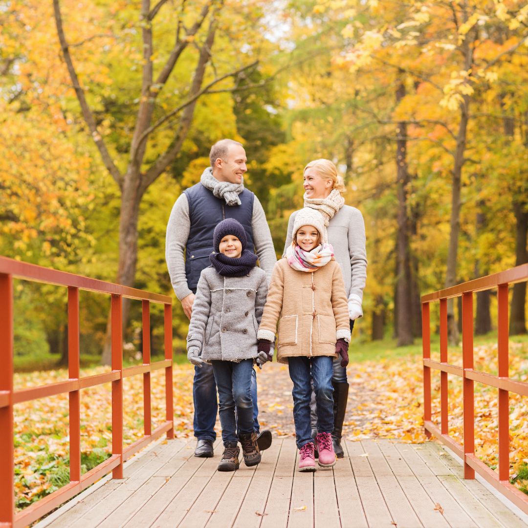 family crossing a footbridge in autumn