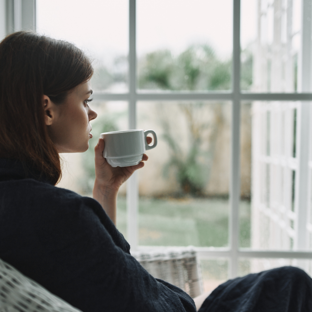 woman drinking coffee near a window