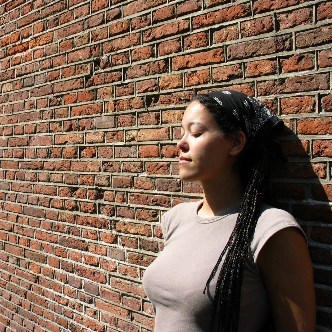 woman with eyes closed leaning against a wall