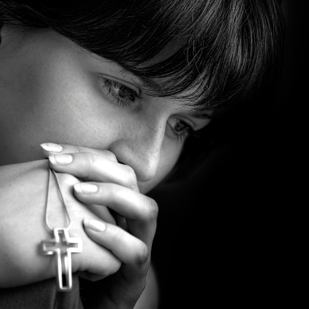 depressed woman holding a cross on a chain