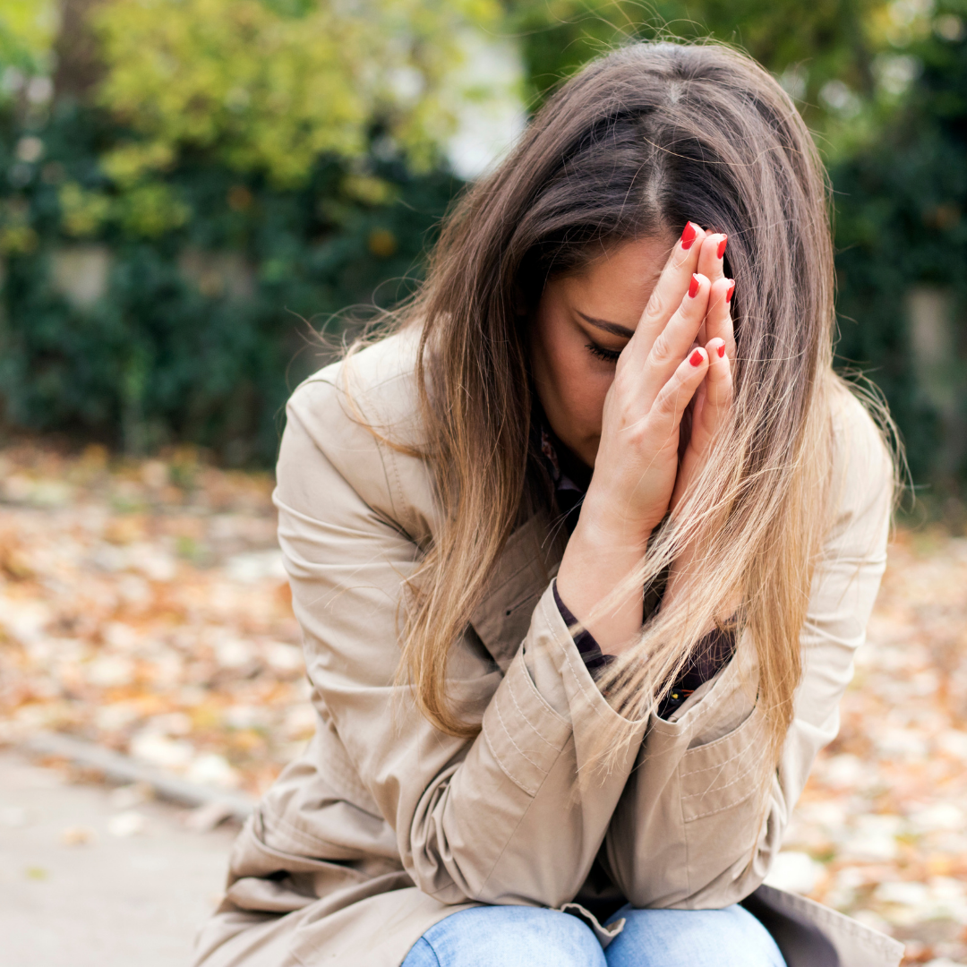 woman praying and crying outdoors in autumn