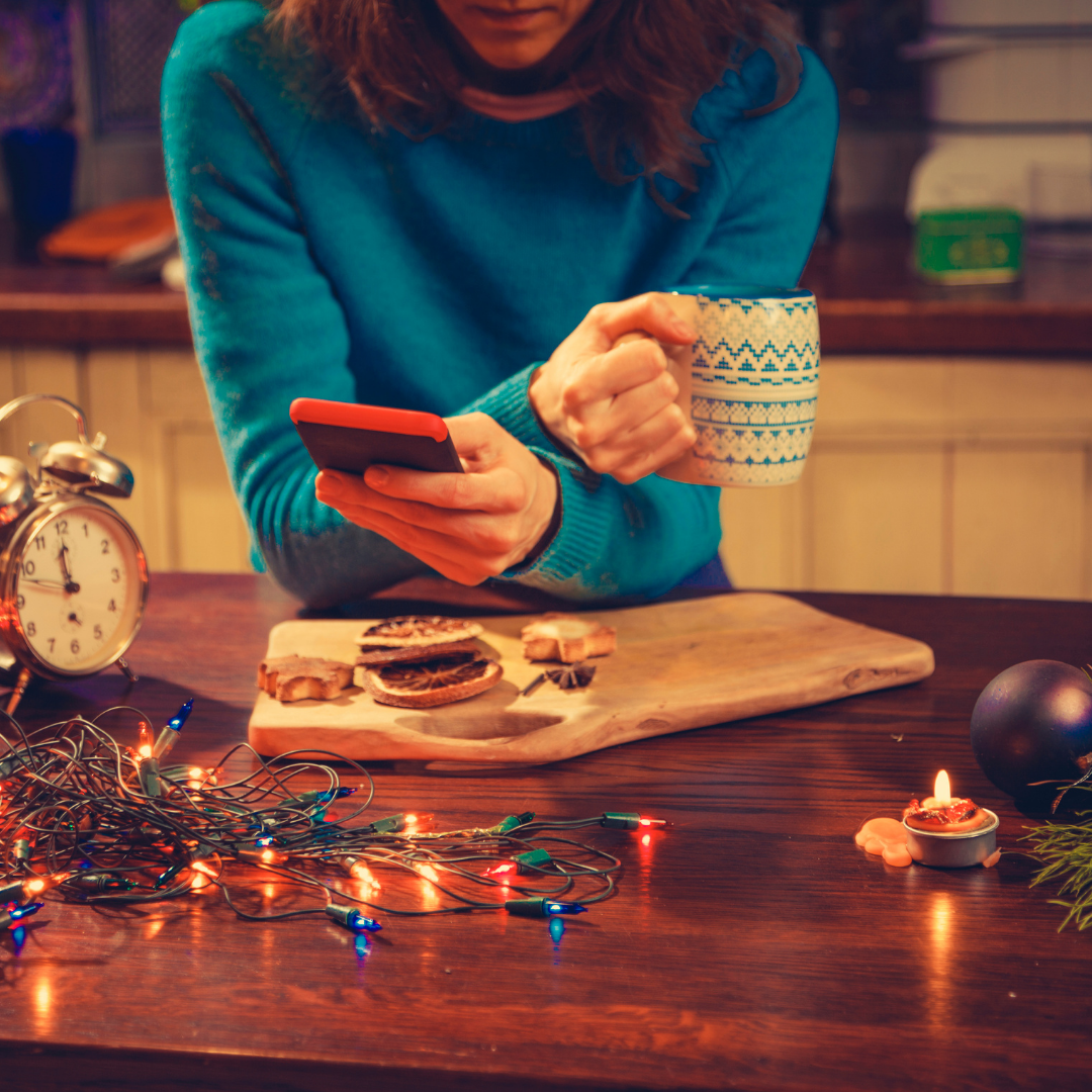 mom with coffee and cell phone surrounded by alarm clock and Christmas decorations