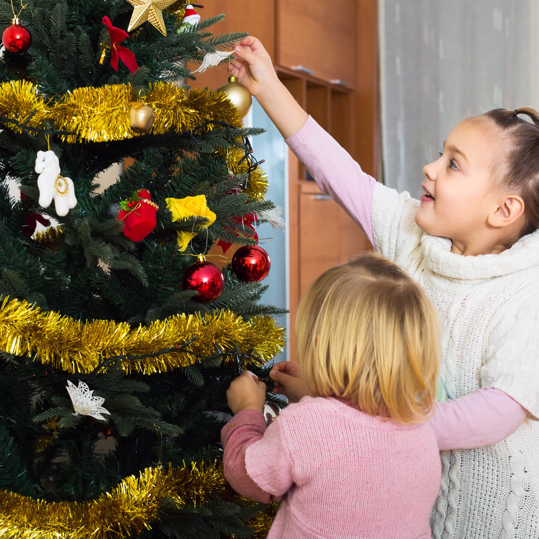 small children hanging ornaments on a Christmas tree