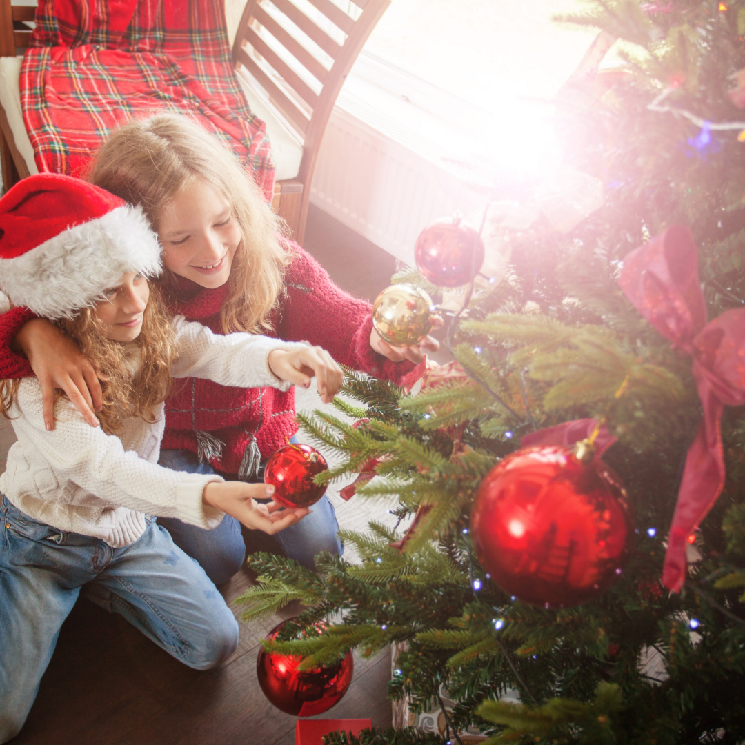 small children hanging ornaments on a Christmas tree