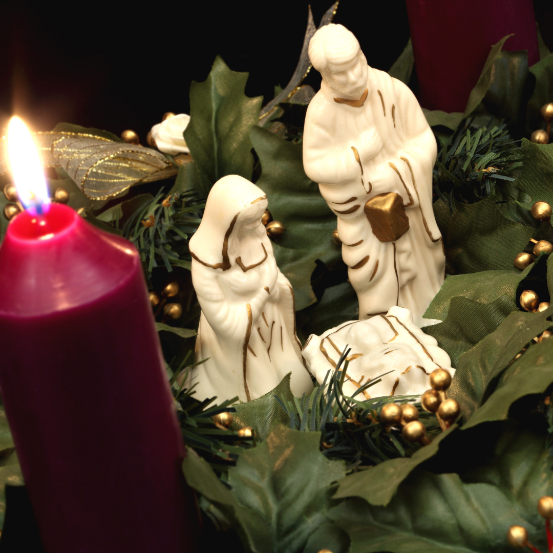 white porcelain Nativity figures next to Advent candle