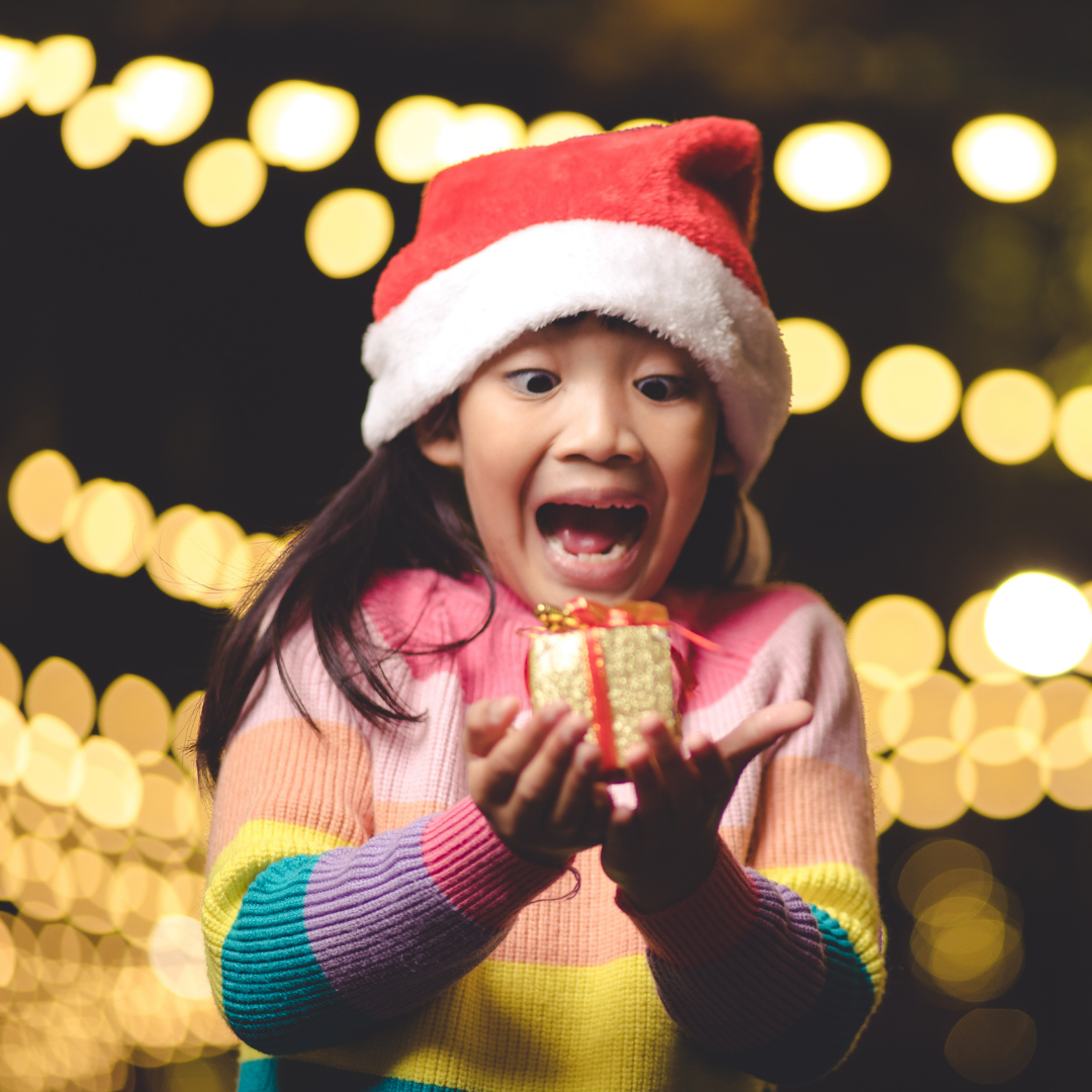 little girl wearing Santa hat and excited over a gift