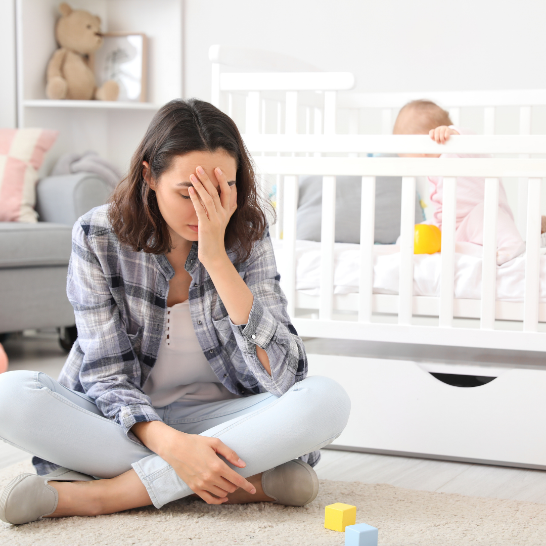 mom sitting on nursery floor near baby in a crib