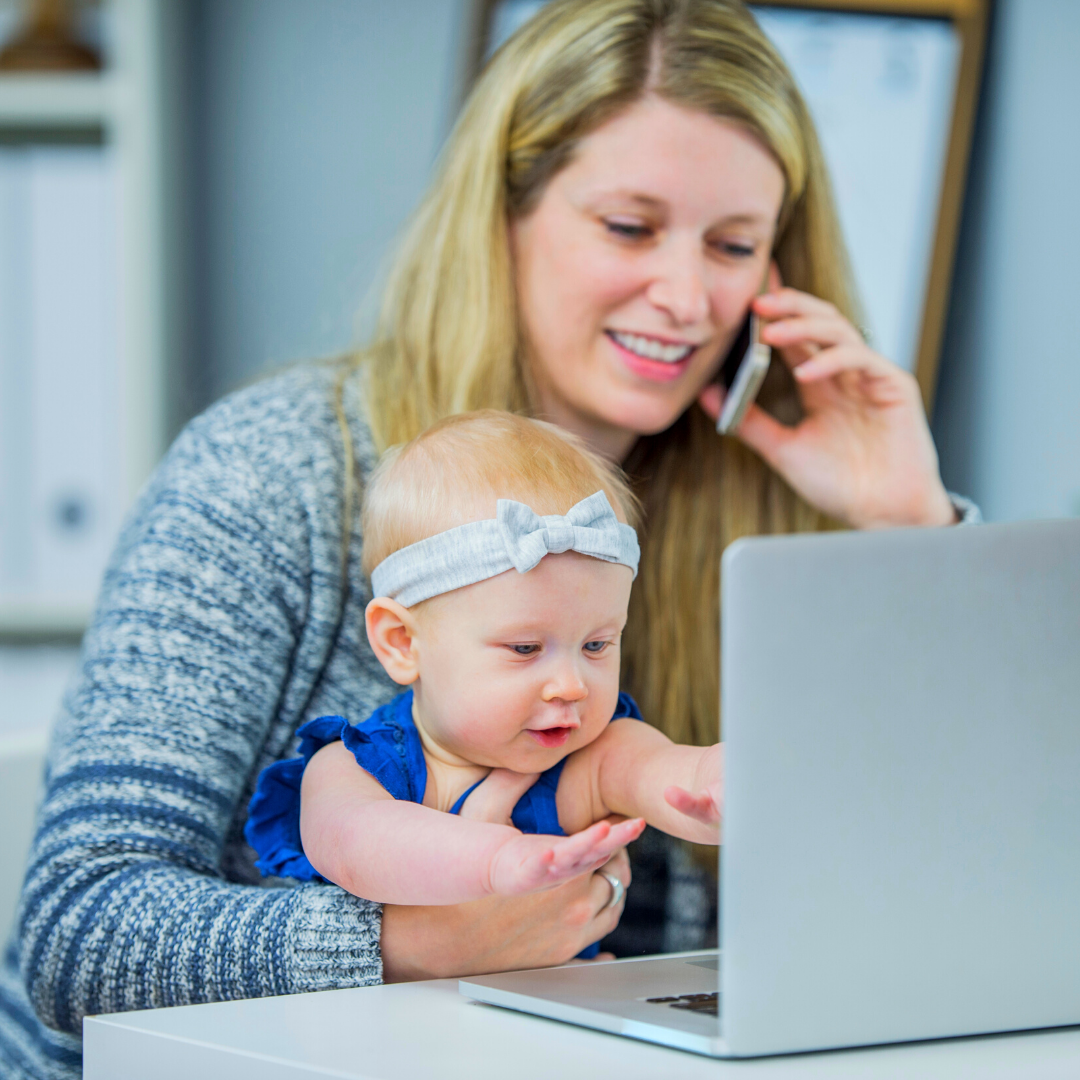 mom on computer and phone with baby on lap