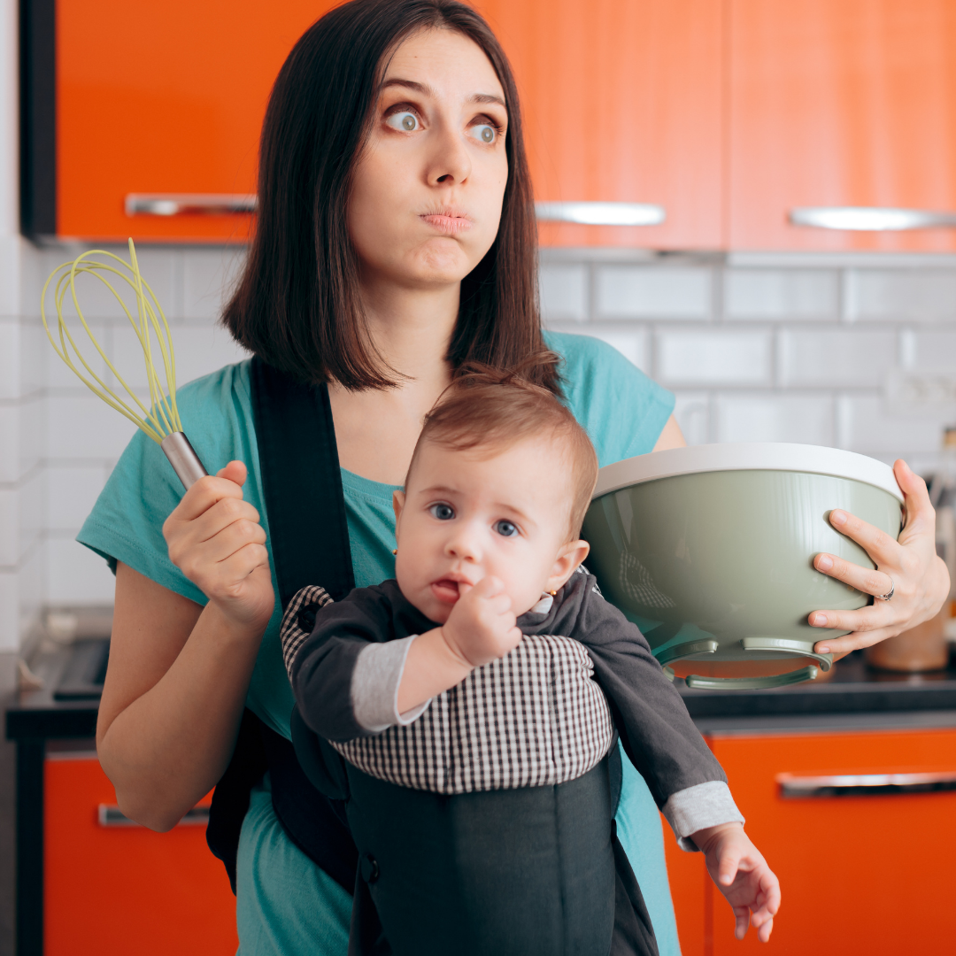 overwhelmed mom cooking while holding baby in a carrier