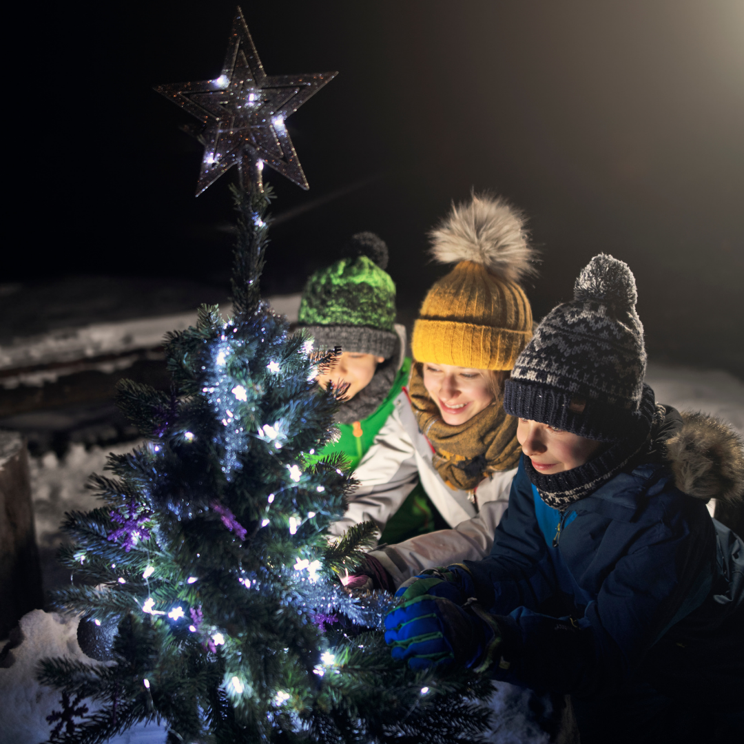 mom and kids decorating outdoor Christmas tree