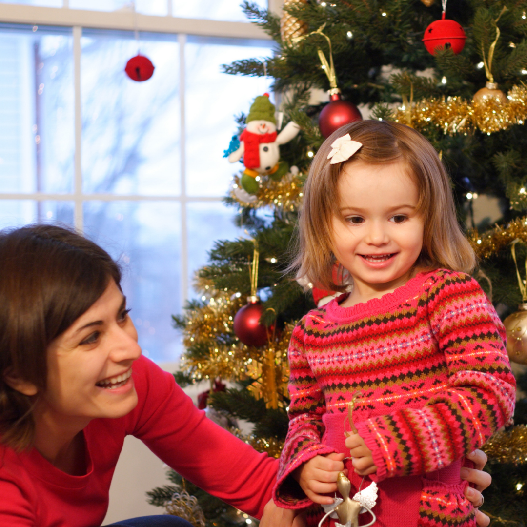 mom and little girl playing near Christmas tree