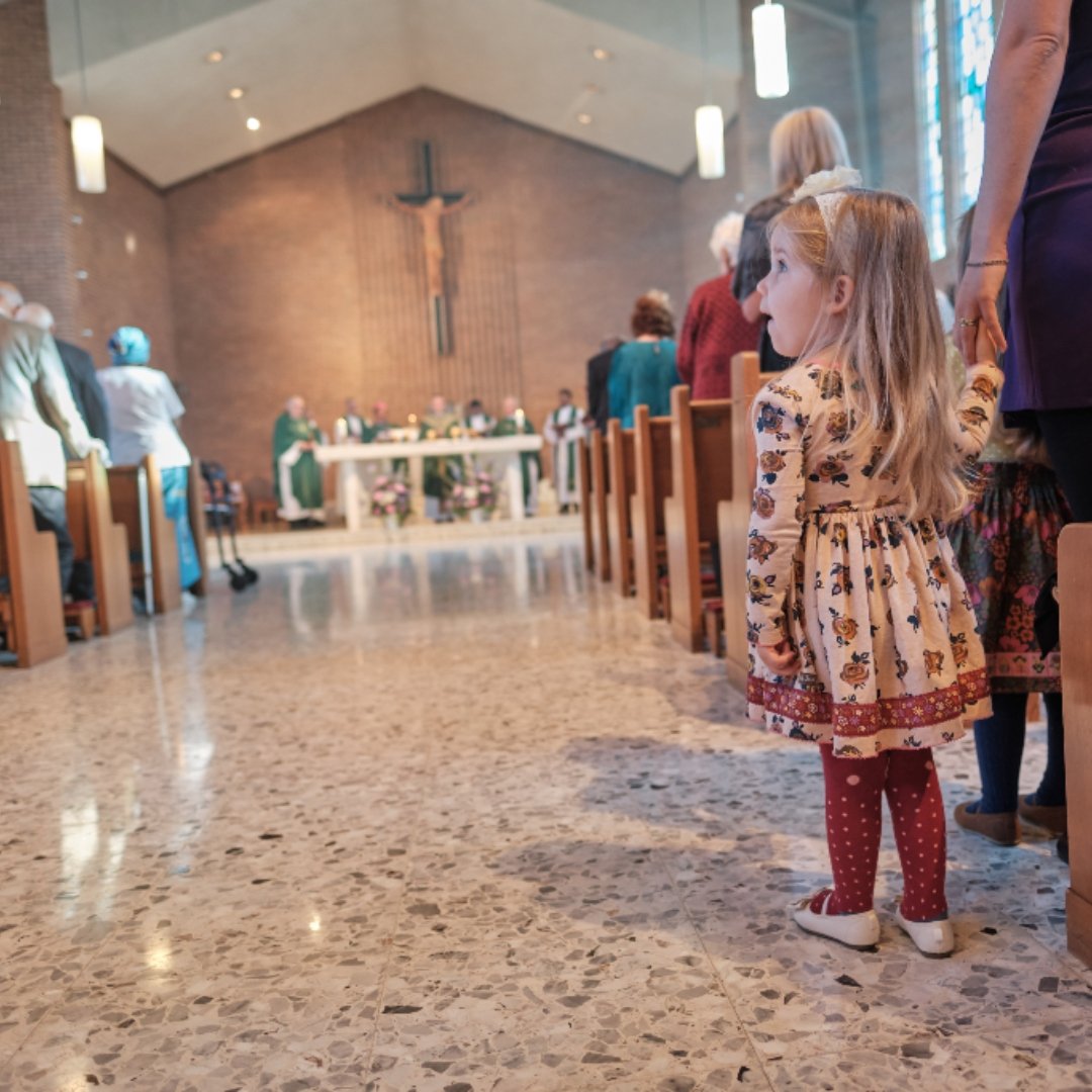 little girl standing in the aisle at Mass