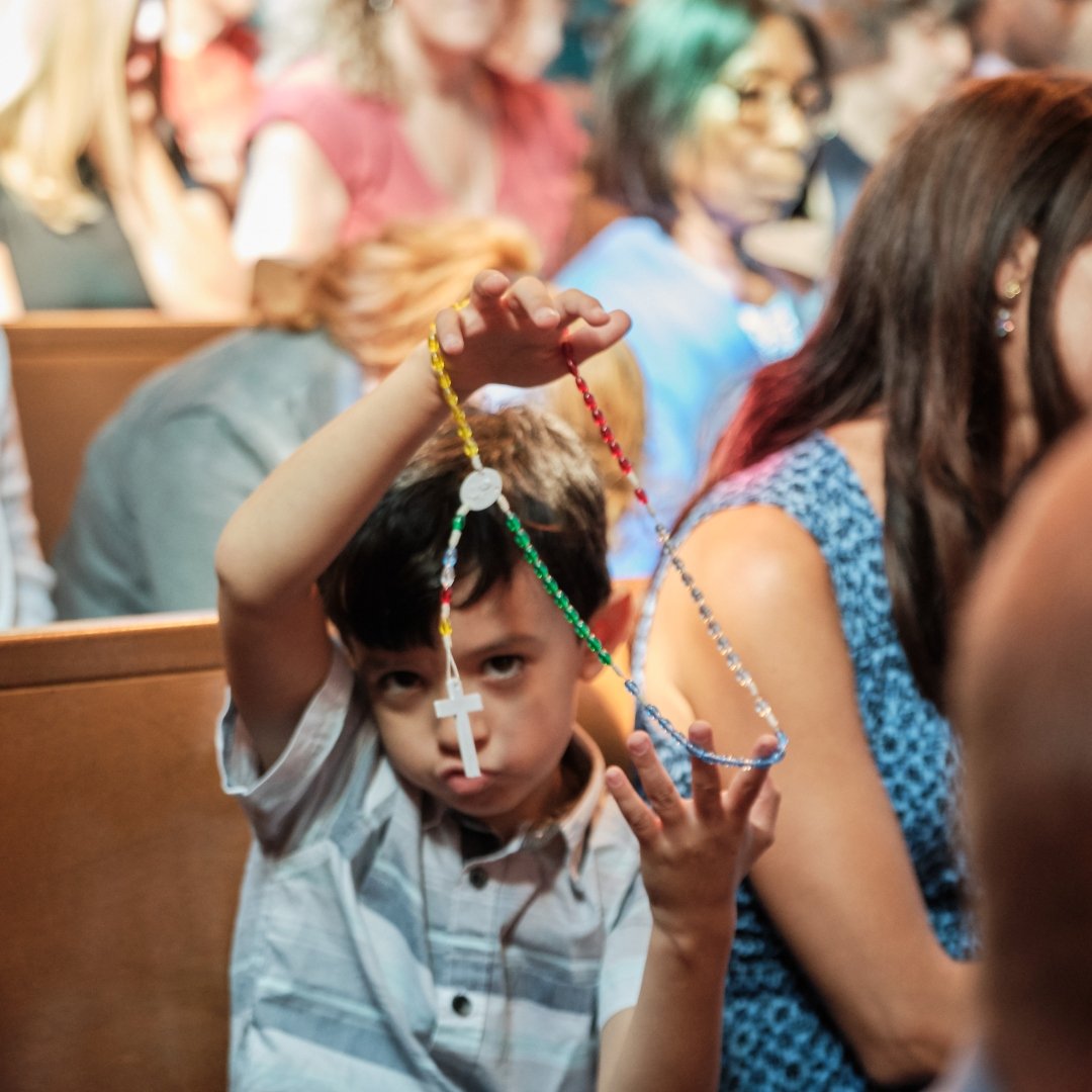 little boy playing with a rosary